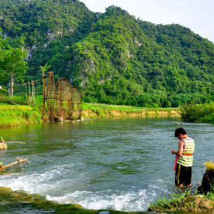 Een visser in de rivier bij de waterwielen van Pu Luong
