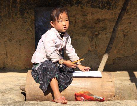 Lokaal Thai-meisje kijkt op van haar schrift in Ha Giang